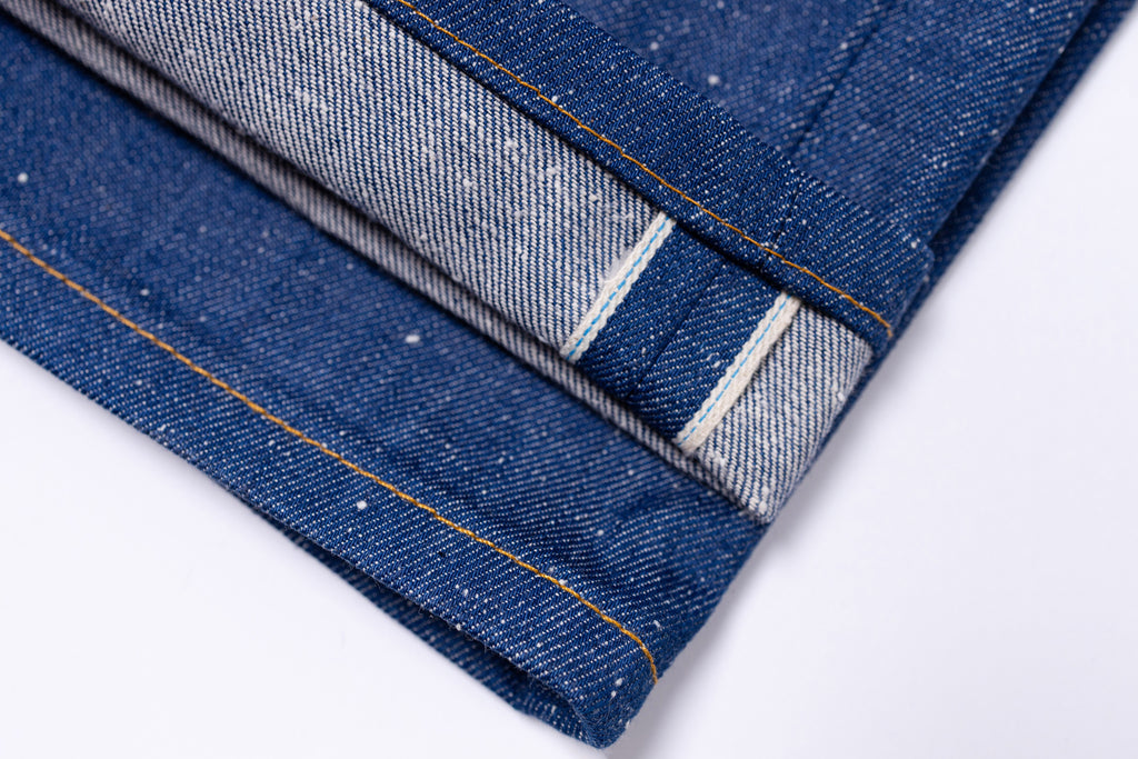 Close-up of denim fabric with visible stitching on a white background