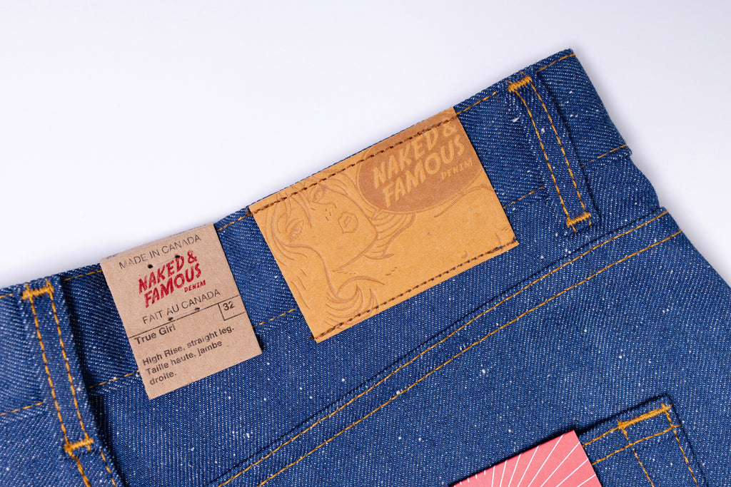 Close-up of blue jeans with a brand label on a white background