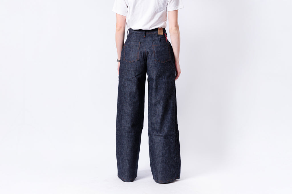 Person wearing dark blue wide-leg jeans on a white background