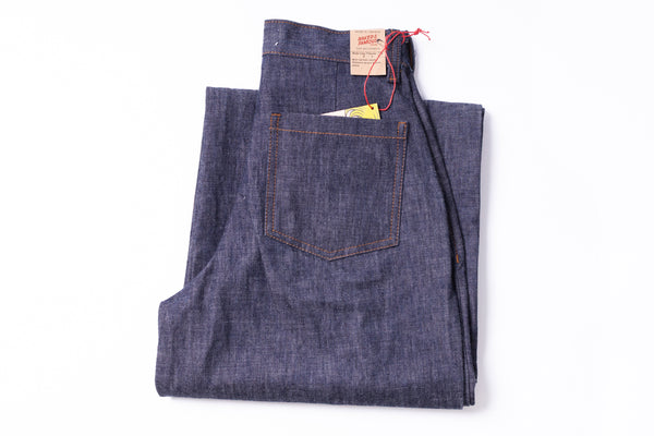 Folded pair of blue jeans with a brand label on a white background