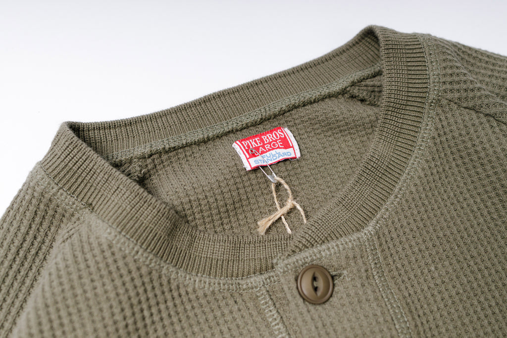 Close-up of a green sweater with a brand tag on a white background