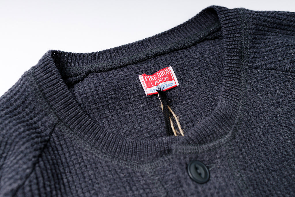 Close-up of a dark gray sweater with a brand label on a white background