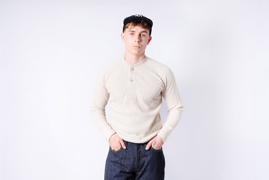 Person wearing a light-colored long-sleeve shirt and dark pants on a white background