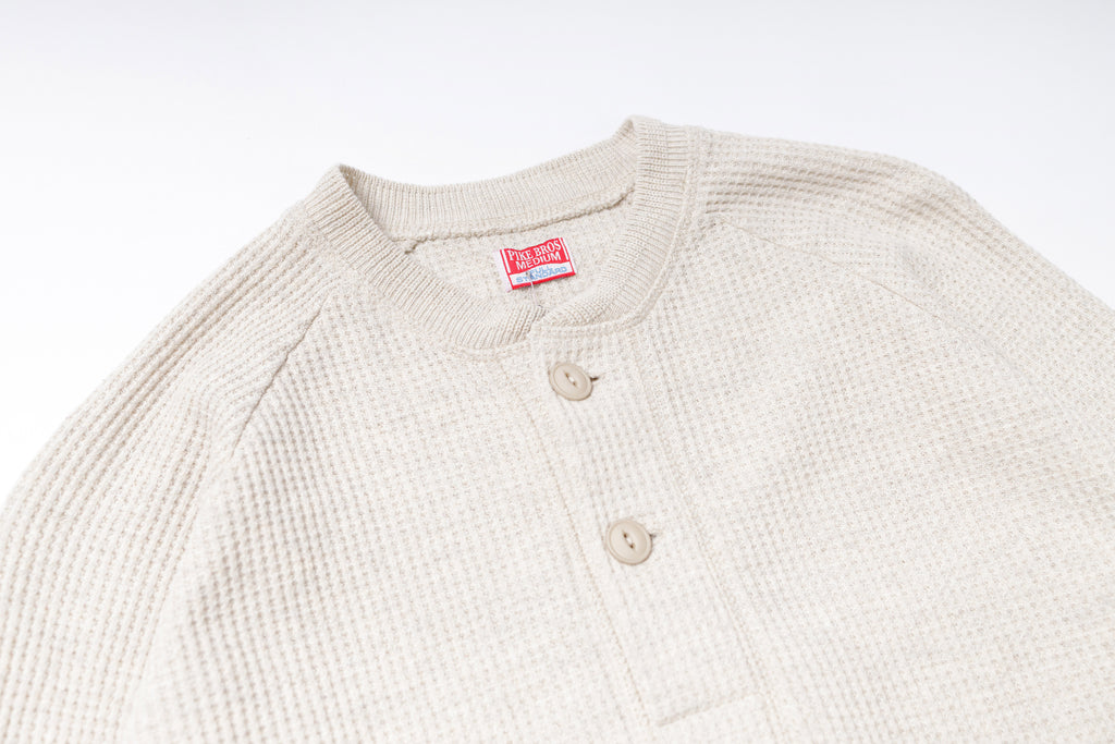 Beige textured shirt with a red label on a white background