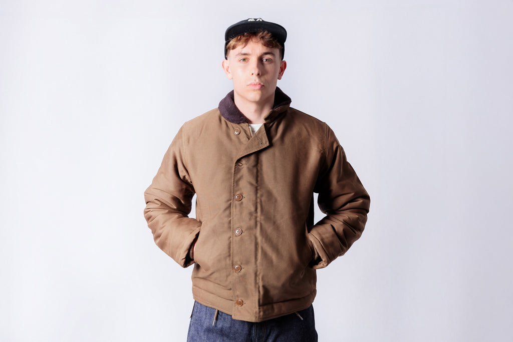 Man wearing a brown jacket and cap on a white background