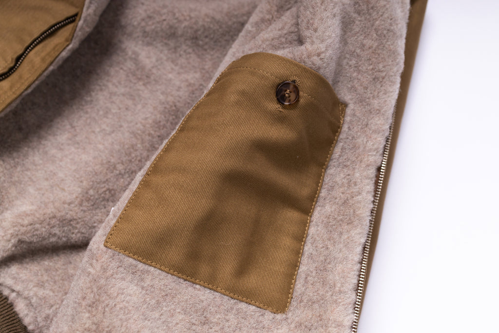 Close-up of a brown fabric patch on a beige garment with a white background