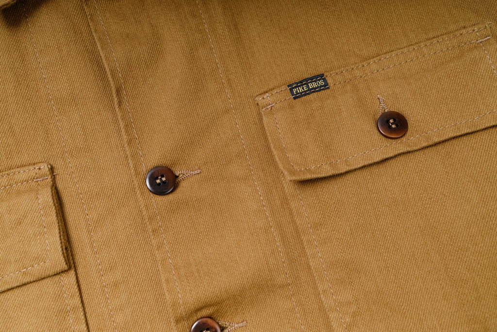 Close-up of a brown jacket with buttons and a brand label.