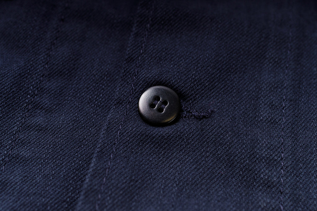 Close-up of a button on a dark blue fabric surface