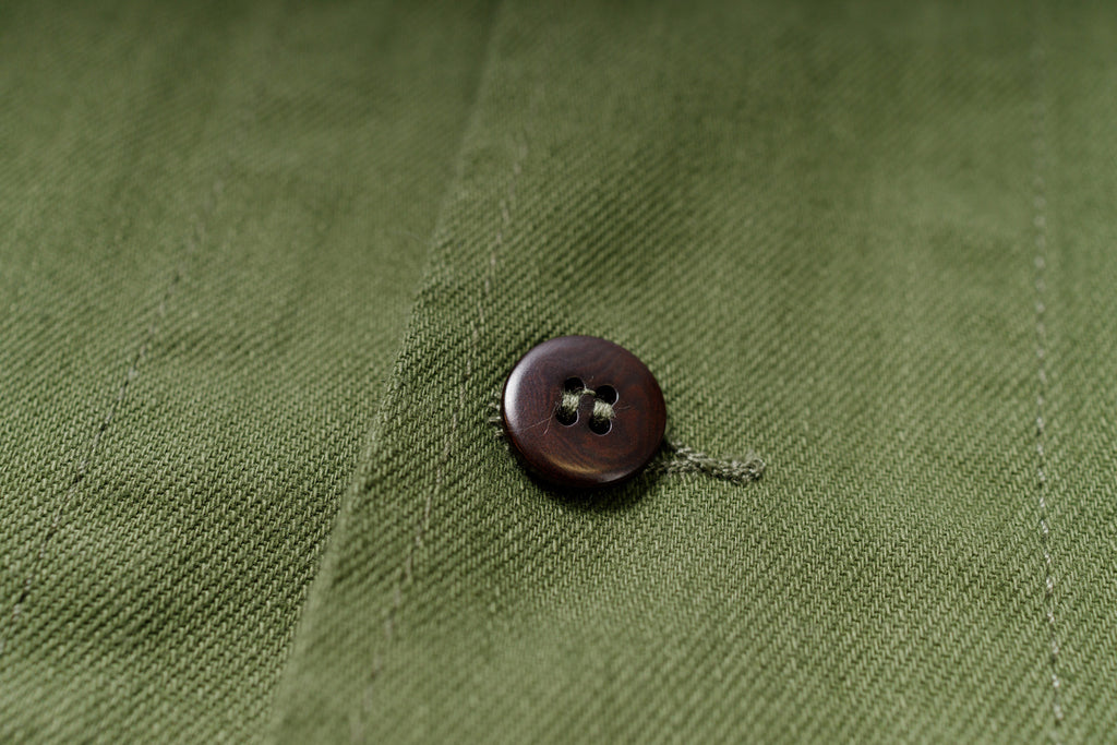 Brown button on green fabric