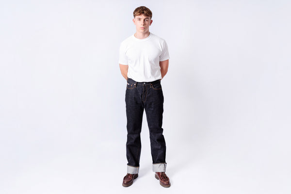Person wearing a white t-shirt and dark jeans on a white background
