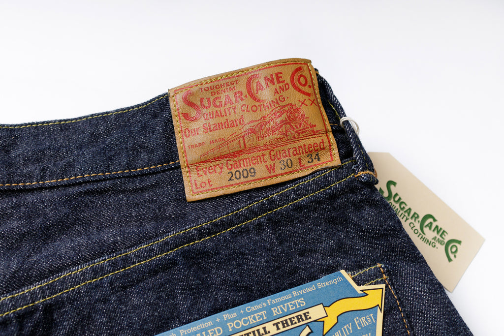 Close-up of a denim product with visible brand labels on a white background