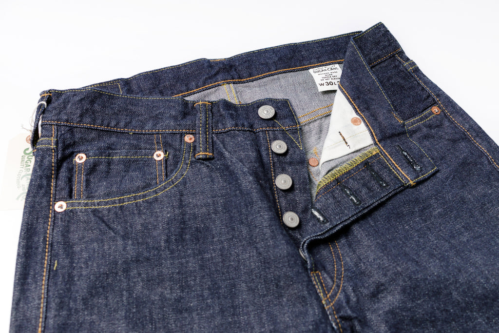 Close-up of a pair of blue jeans with button details on a white background
