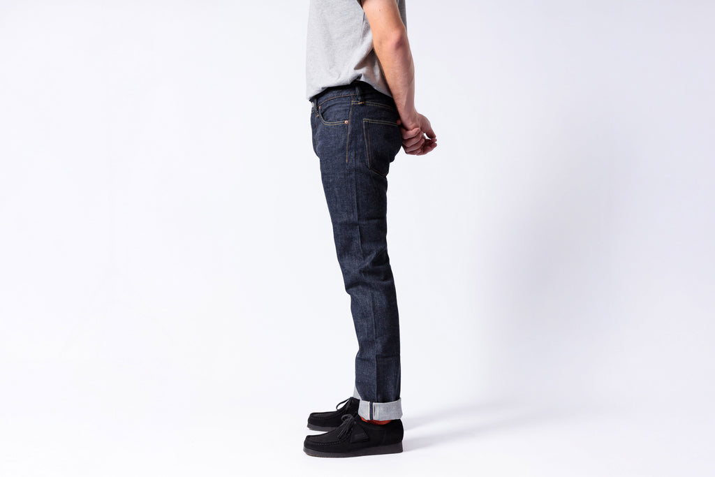 Person wearing dark blue jeans on a white background