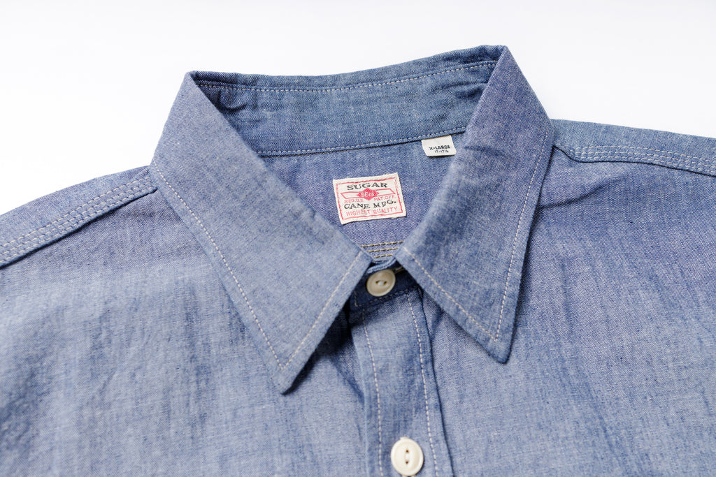 Close-up of a blue denim shirt with a brand label on a white background