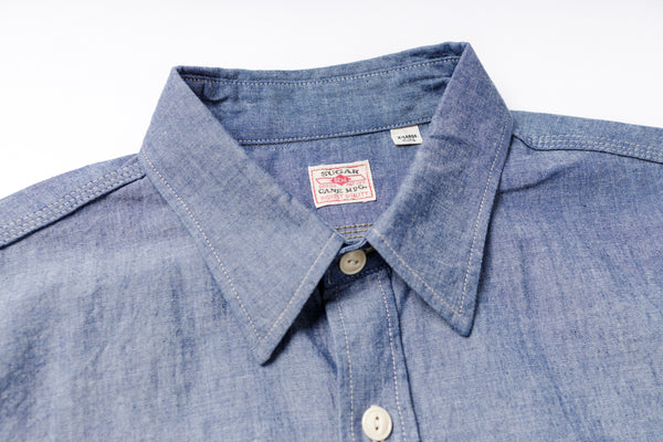 Close-up of a blue denim shirt with a brand label on a white background