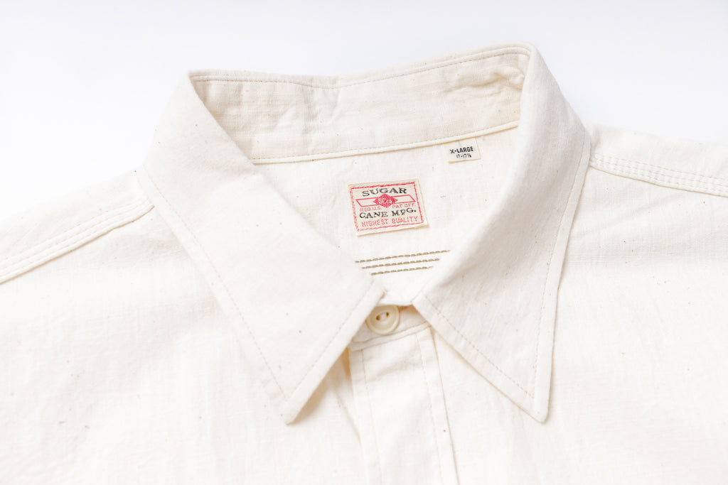 Close-up of a white shirt with a brand label on a white background