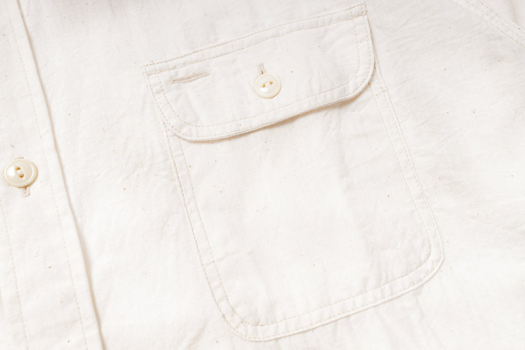 Close-up of a white denim pocket with buttons on a light background