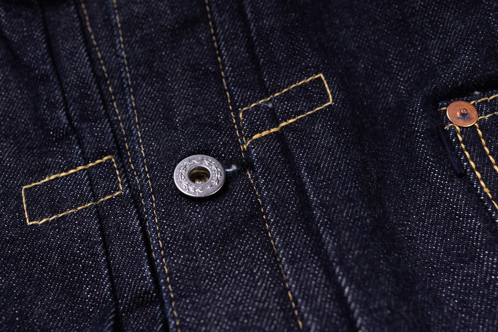 Close-up of a button on a dark blue denim fabric