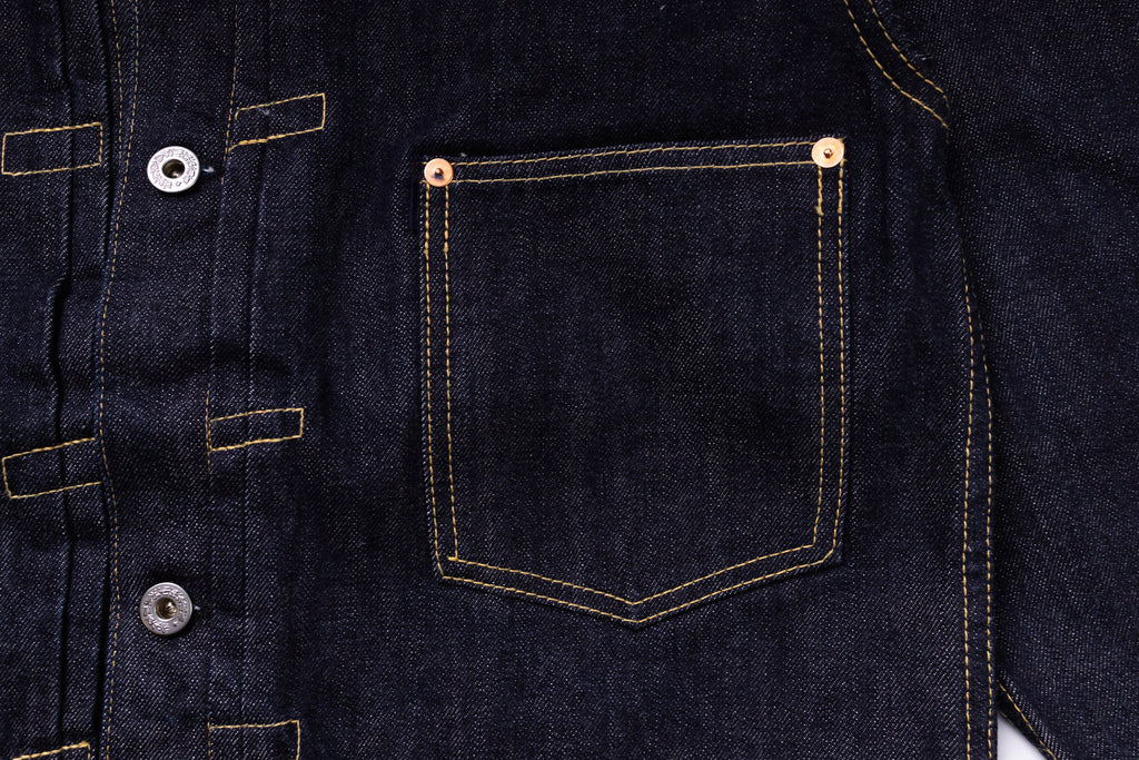 Close-up of a dark blue denim jacket with buttons and a pocket.