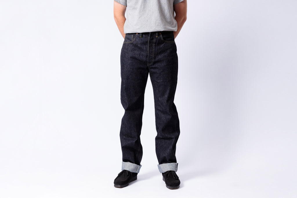 Person wearing dark jeans and a gray shirt on a white background
