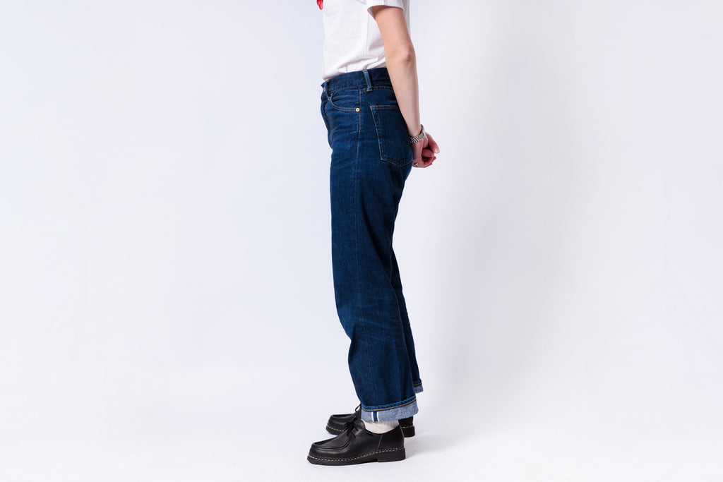 Person wearing blue jeans and black shoes on a white background