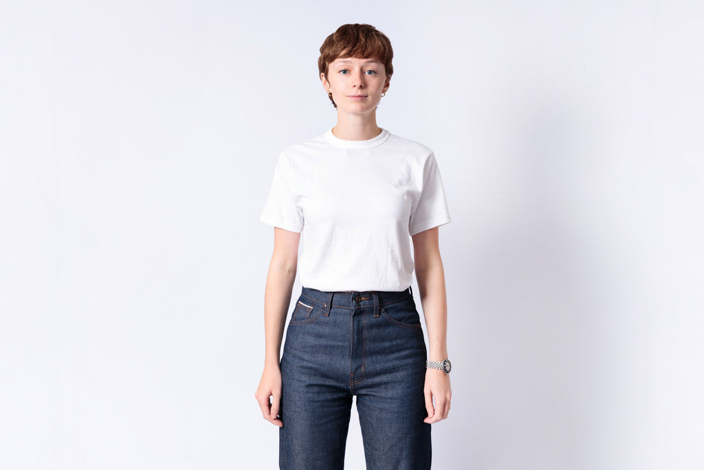 Person wearing a white t-shirt and blue jeans on a plain background