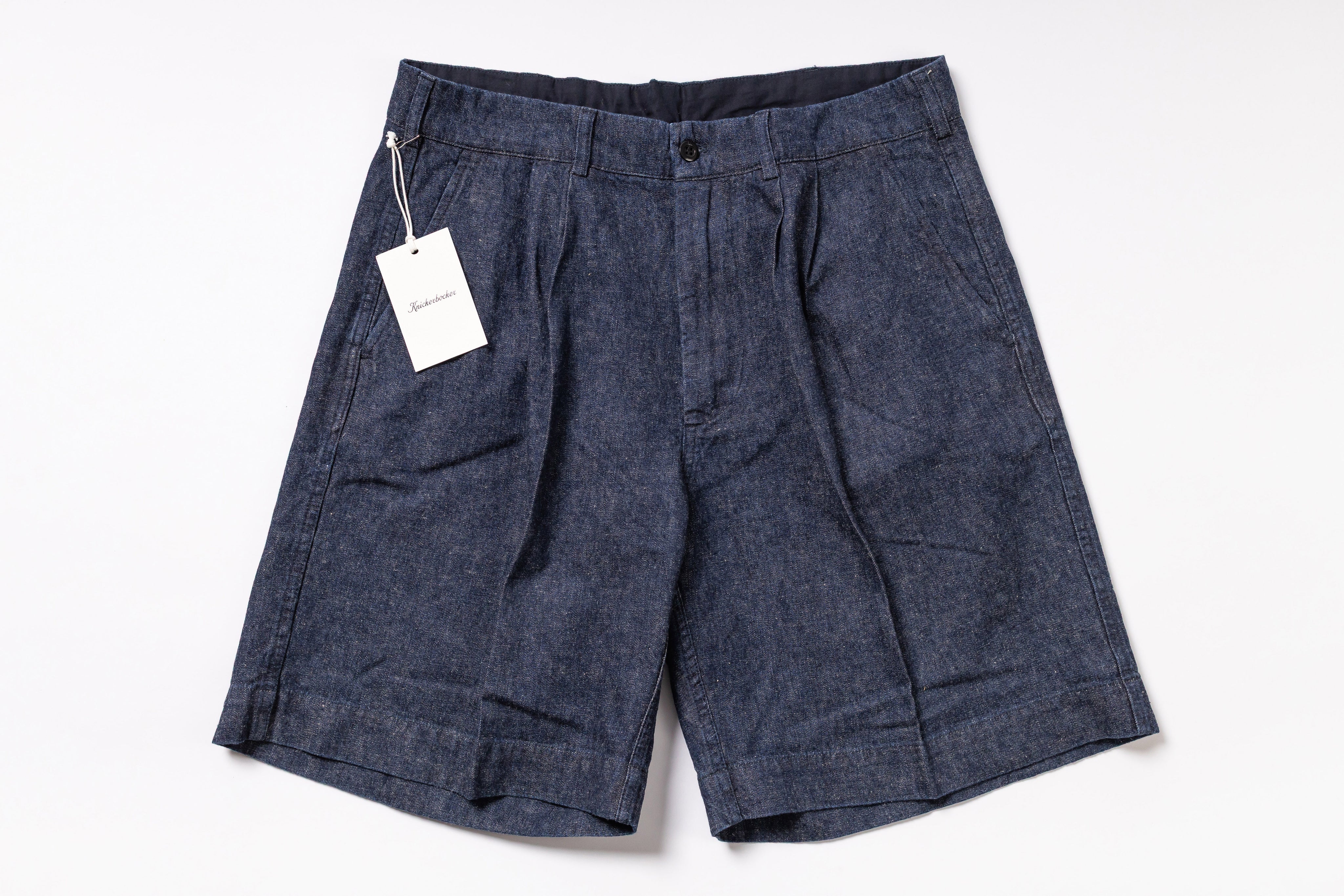 Pair of dark denim shorts with a tag on a white background