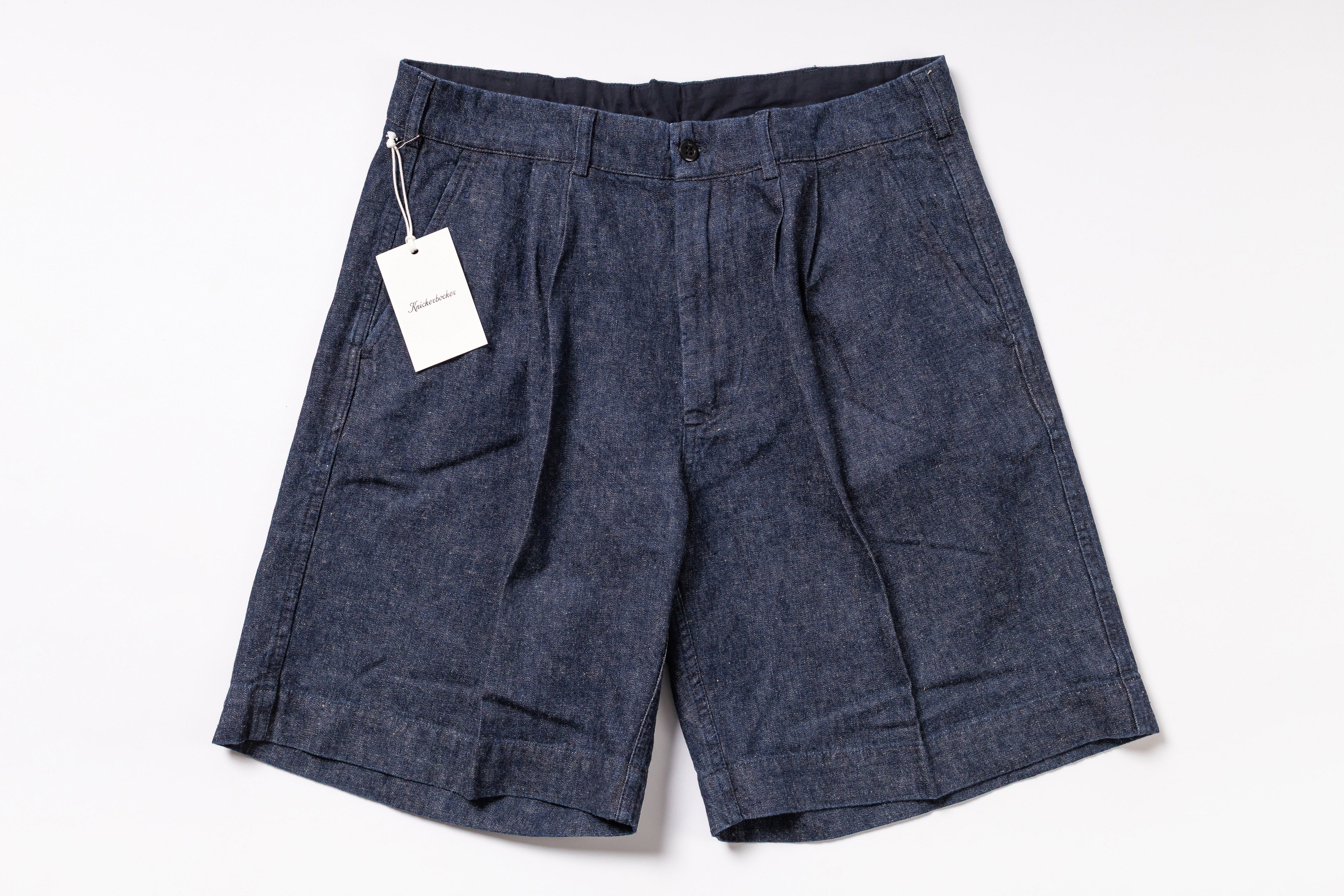 Pair of dark denim shorts with a tag on a white background