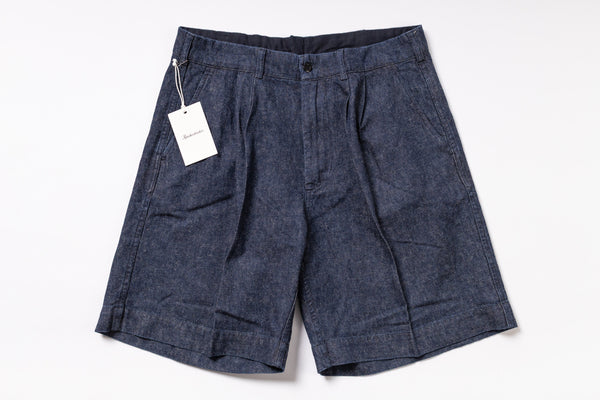 Pair of dark denim shorts with a tag on a white background