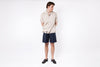 Person wearing a beige shirt and dark shorts on a white background
