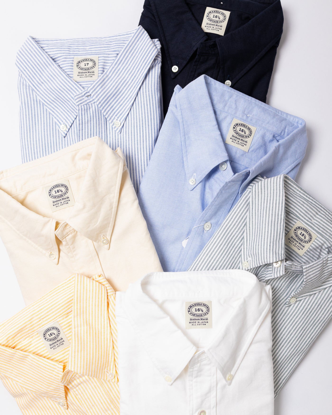 Collection of folded dress shirts in various colors on a white background