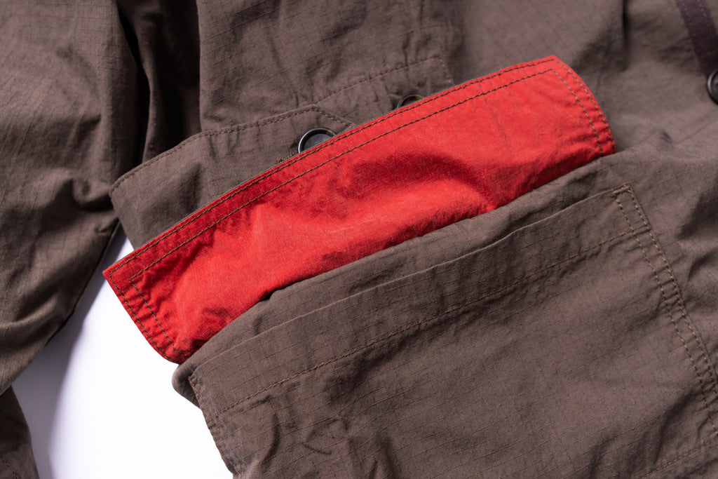 Brown jacket with a red lining peeking out from a pocket