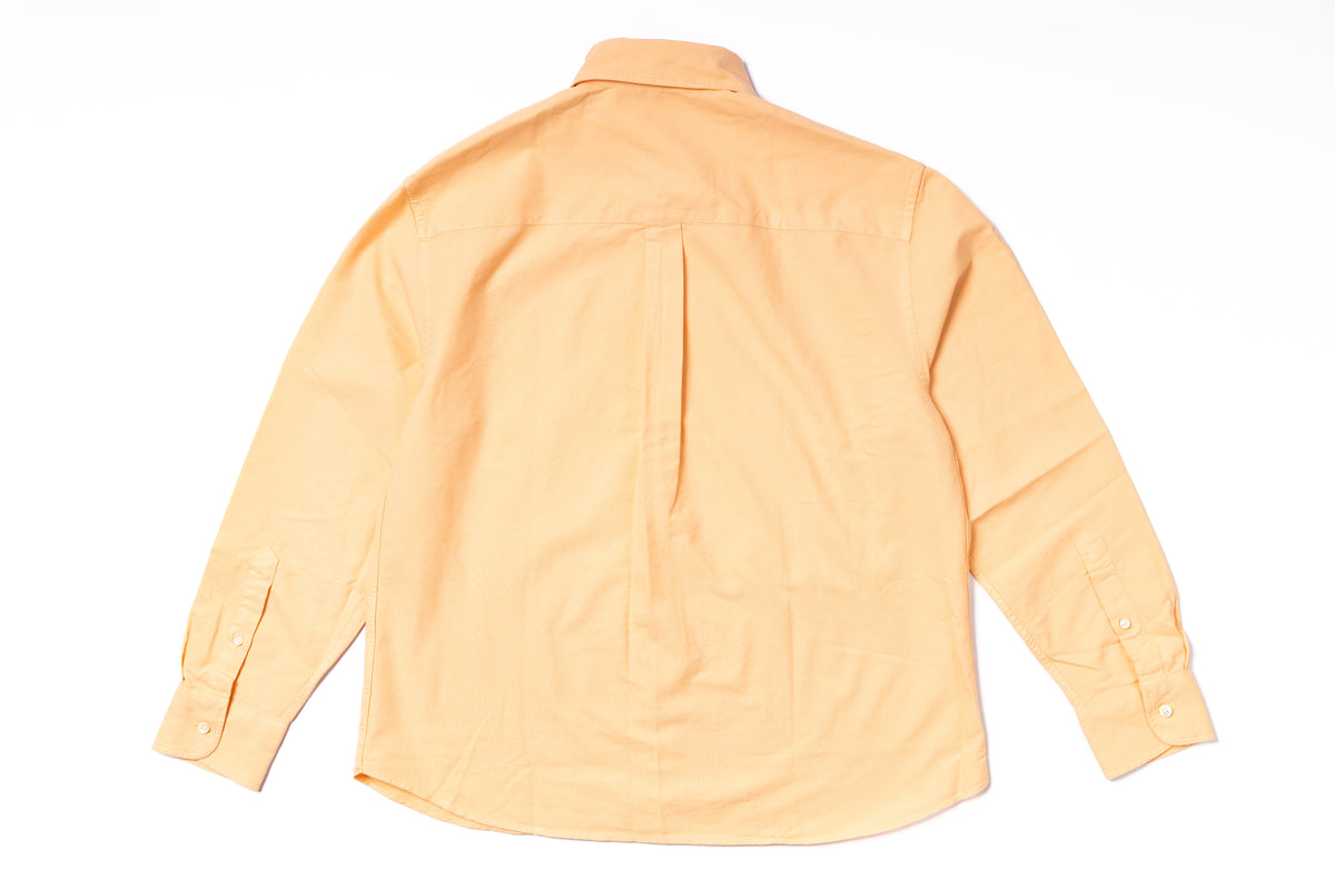 Back view of a light orange shirt on a white background