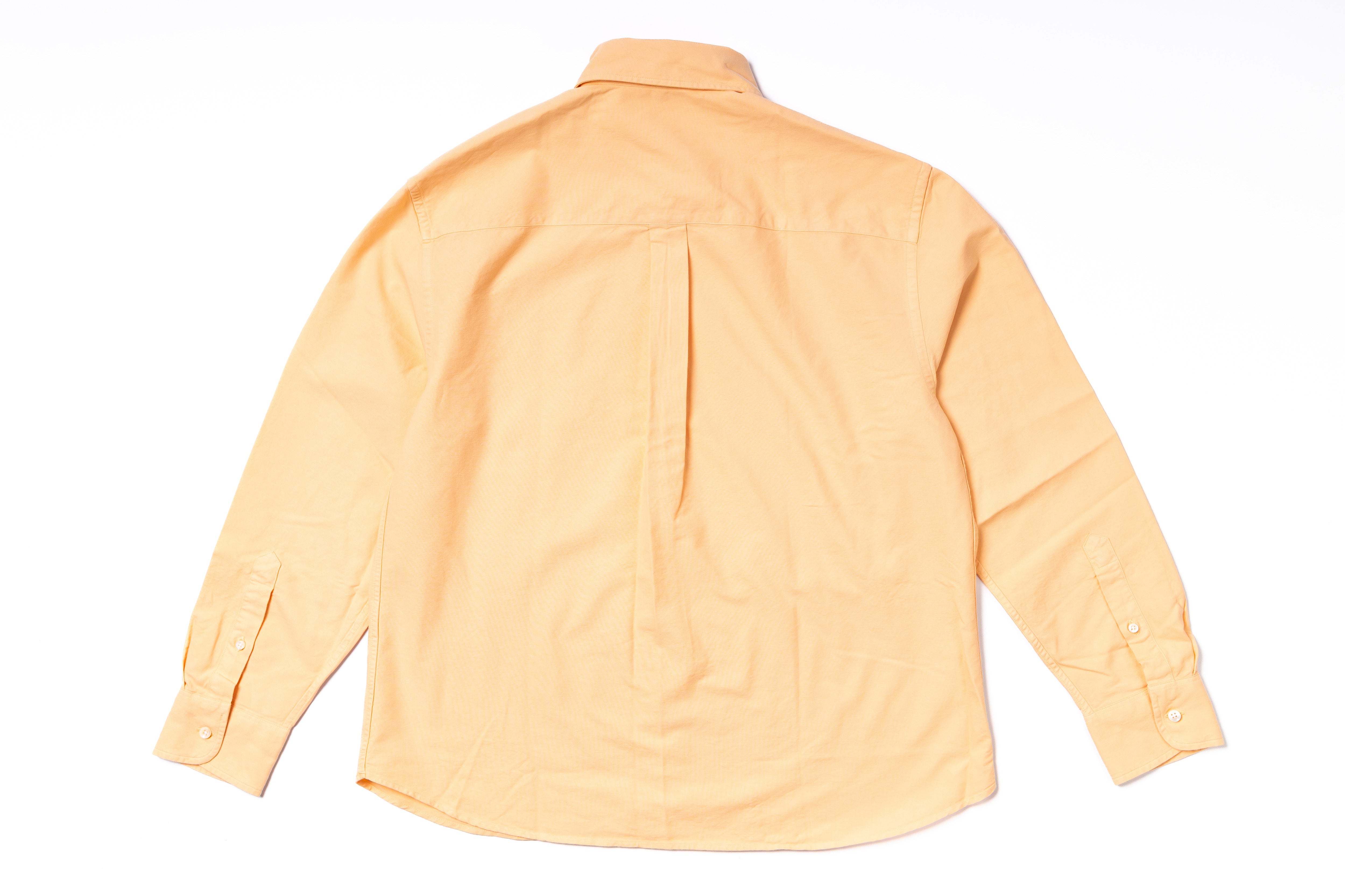 Back view of a light orange shirt on a white background