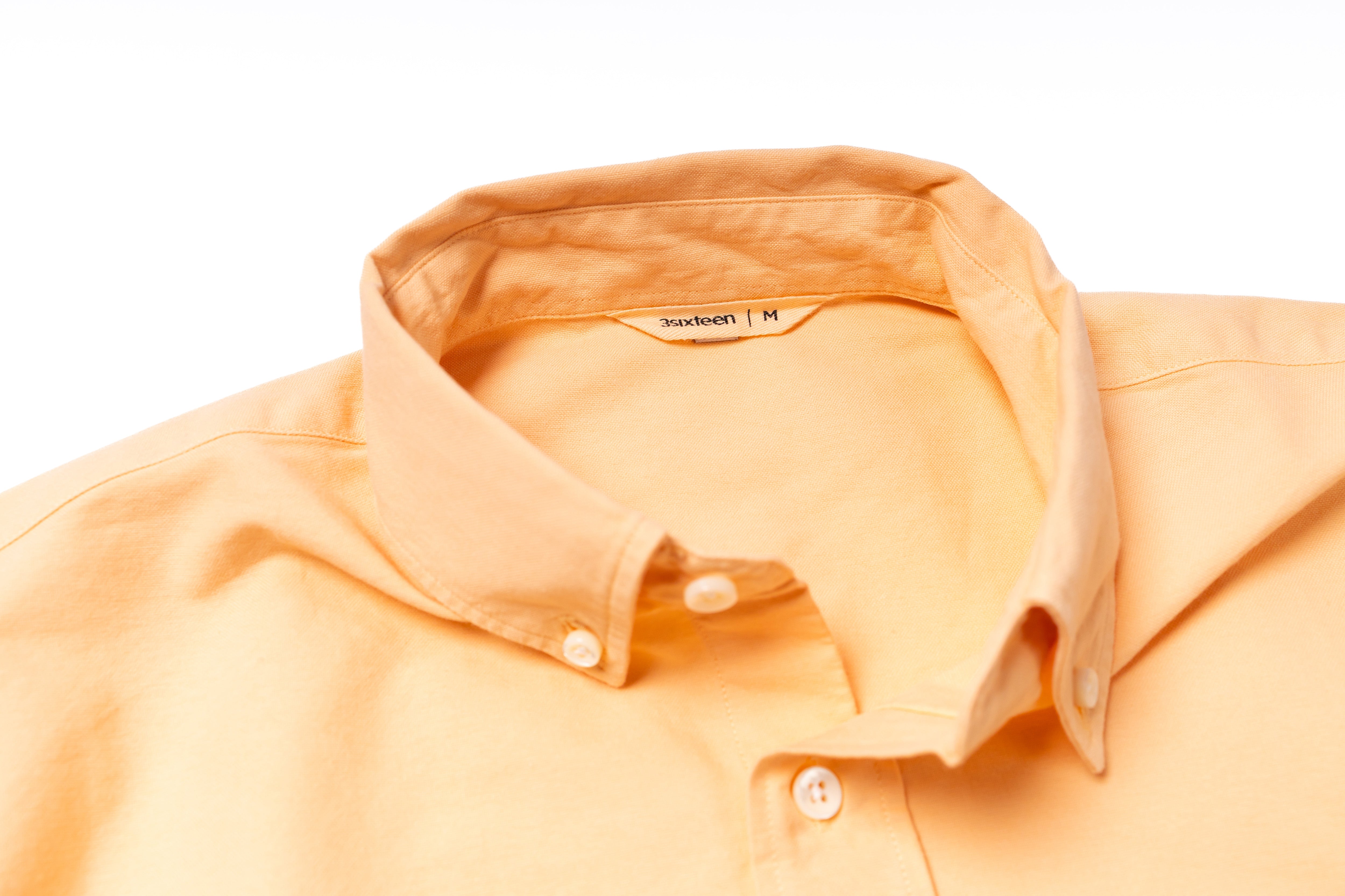 Orange shirt with collar and buttons on a white background