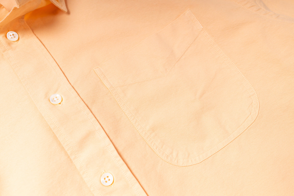 Close-up of a light peach-colored shirt with buttons and a pocket.