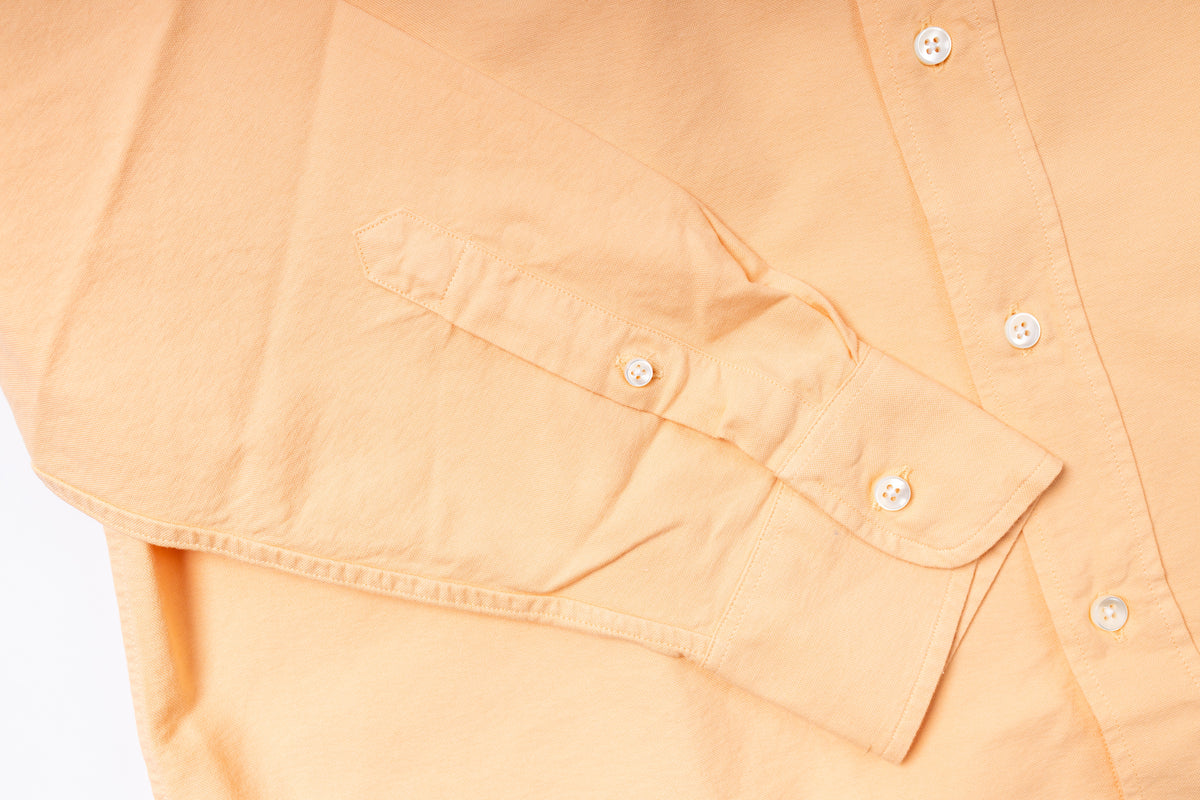Close-up of a peach-colored shirt with button details on a light gray background