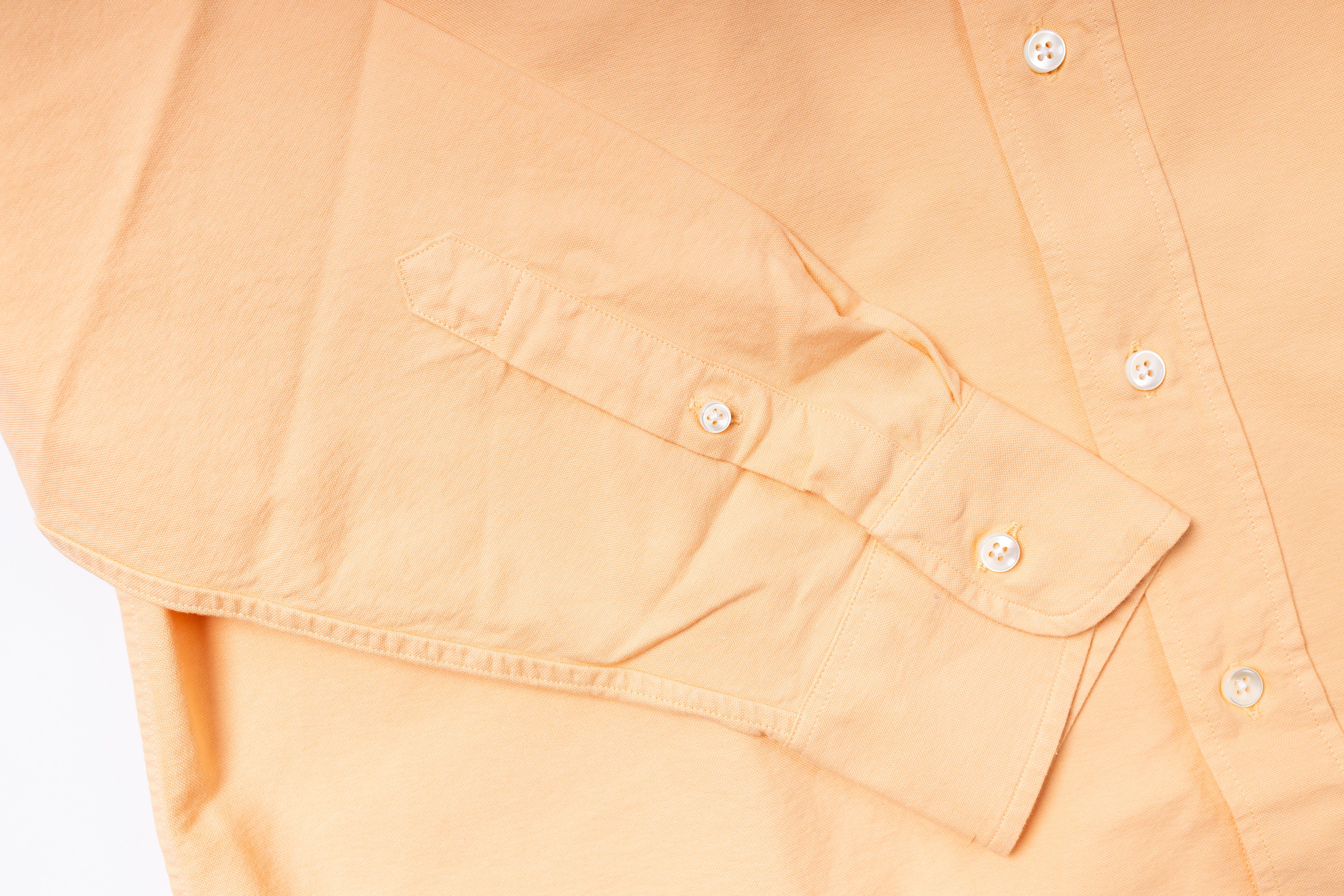 Close-up of a peach-colored shirt with button details on a light gray background
