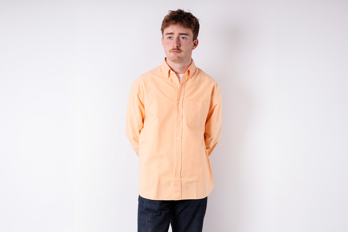 Person wearing a light orange shirt against a white background