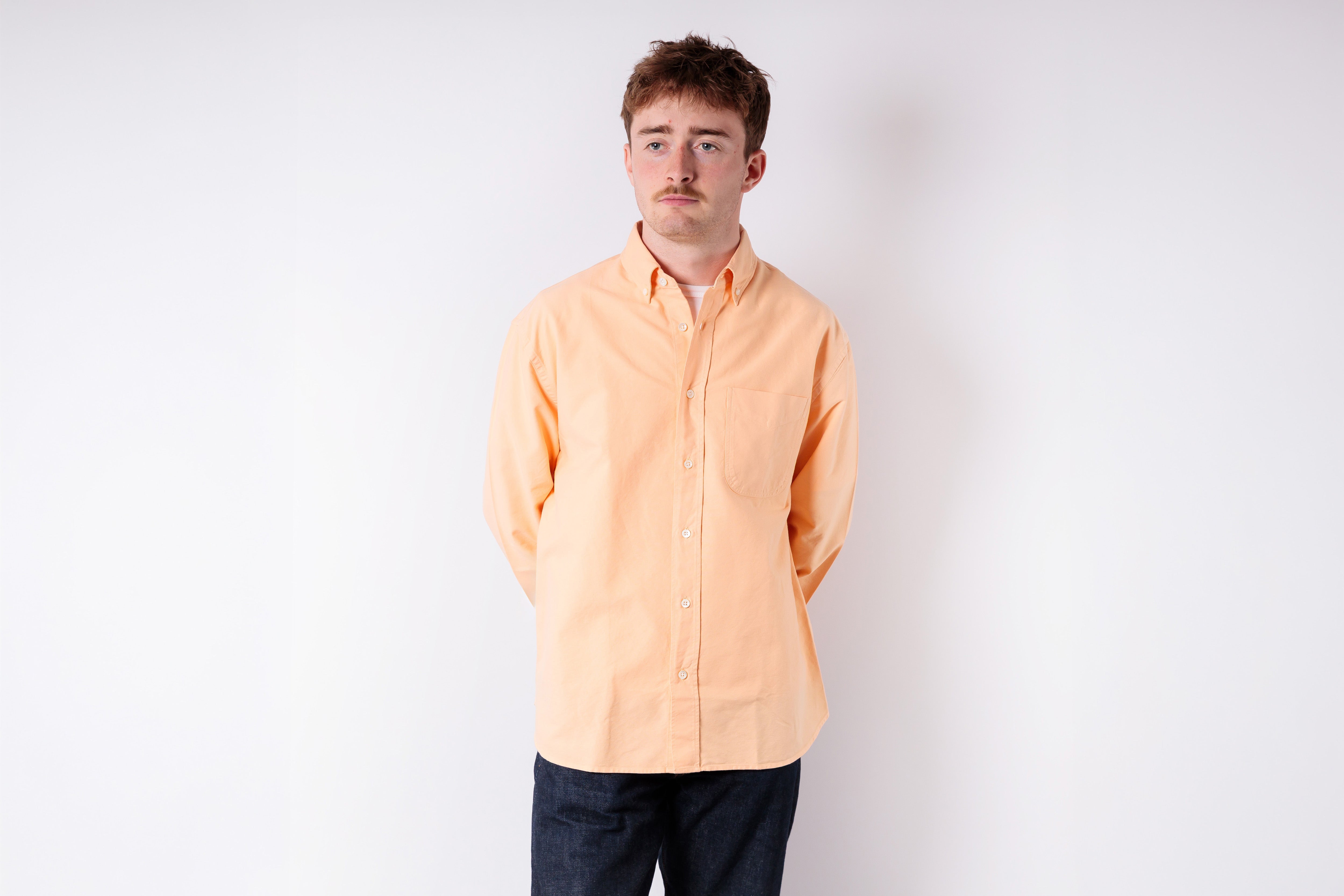 Person wearing a light orange shirt against a white background
