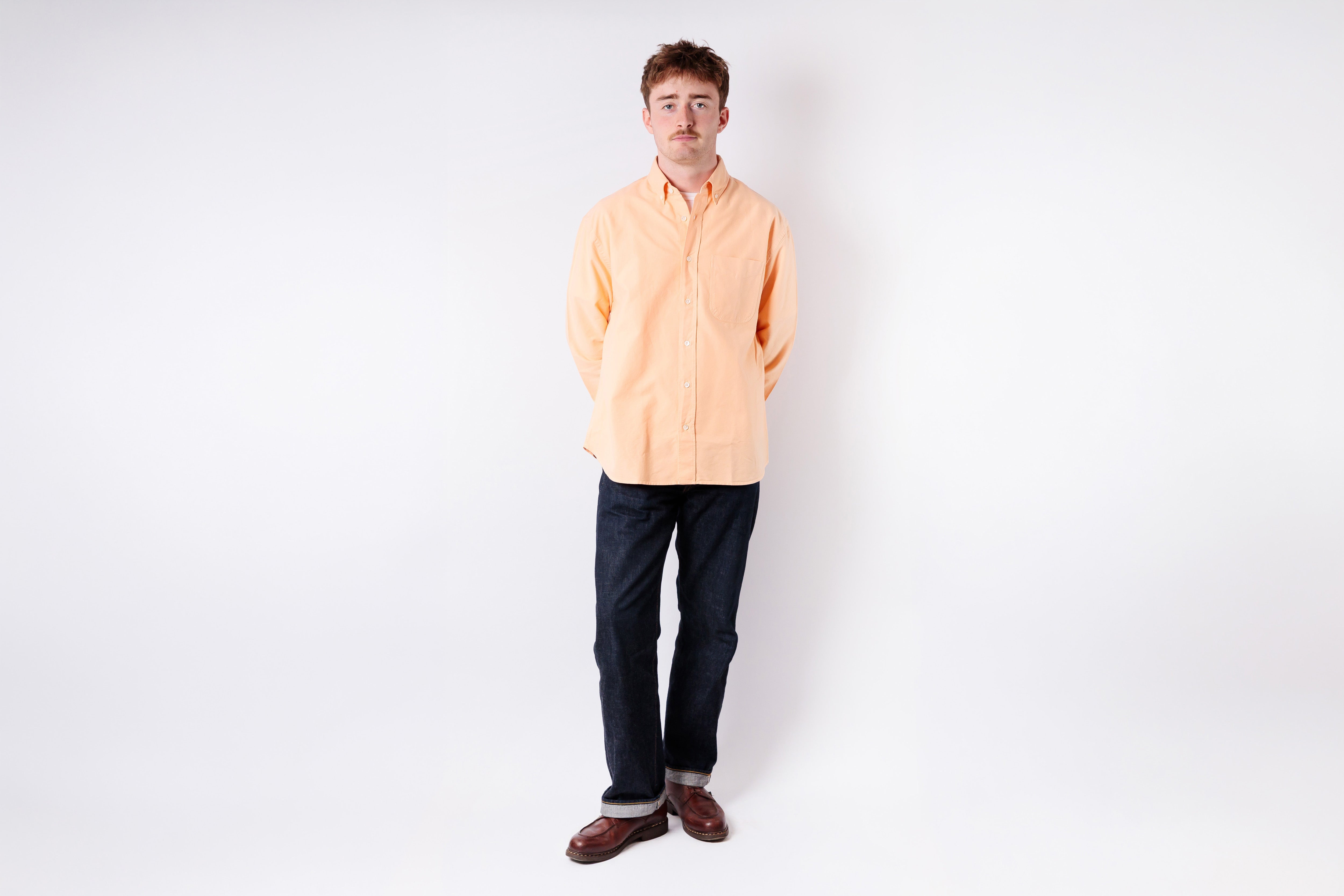 Person wearing a light orange shirt against a white background