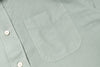 Close-up of a light gray shirt with a pocket and button details.