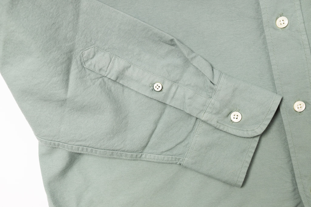 Close-up of a light gray shirt with button details on a white background