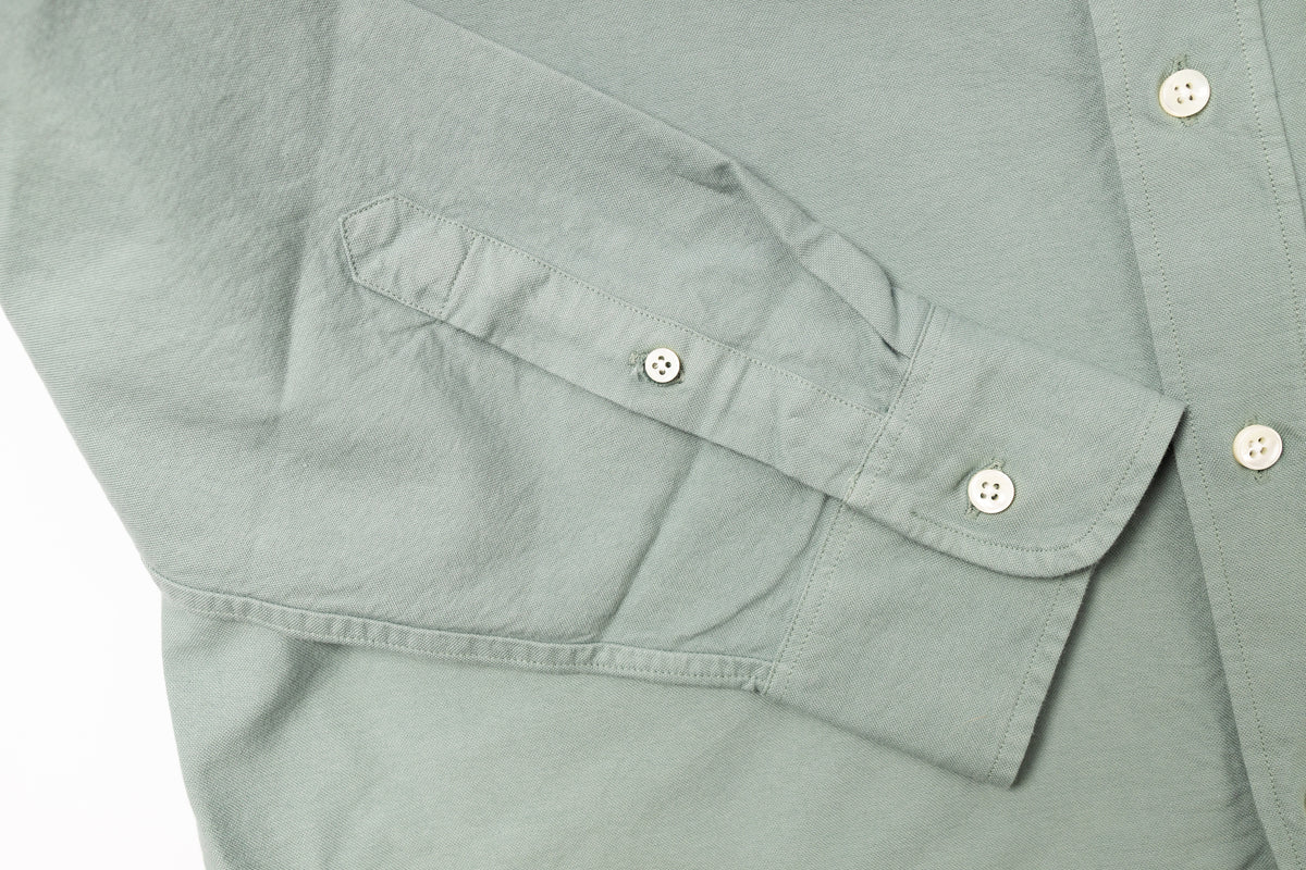 Close-up of a light gray shirt with button details on a white background