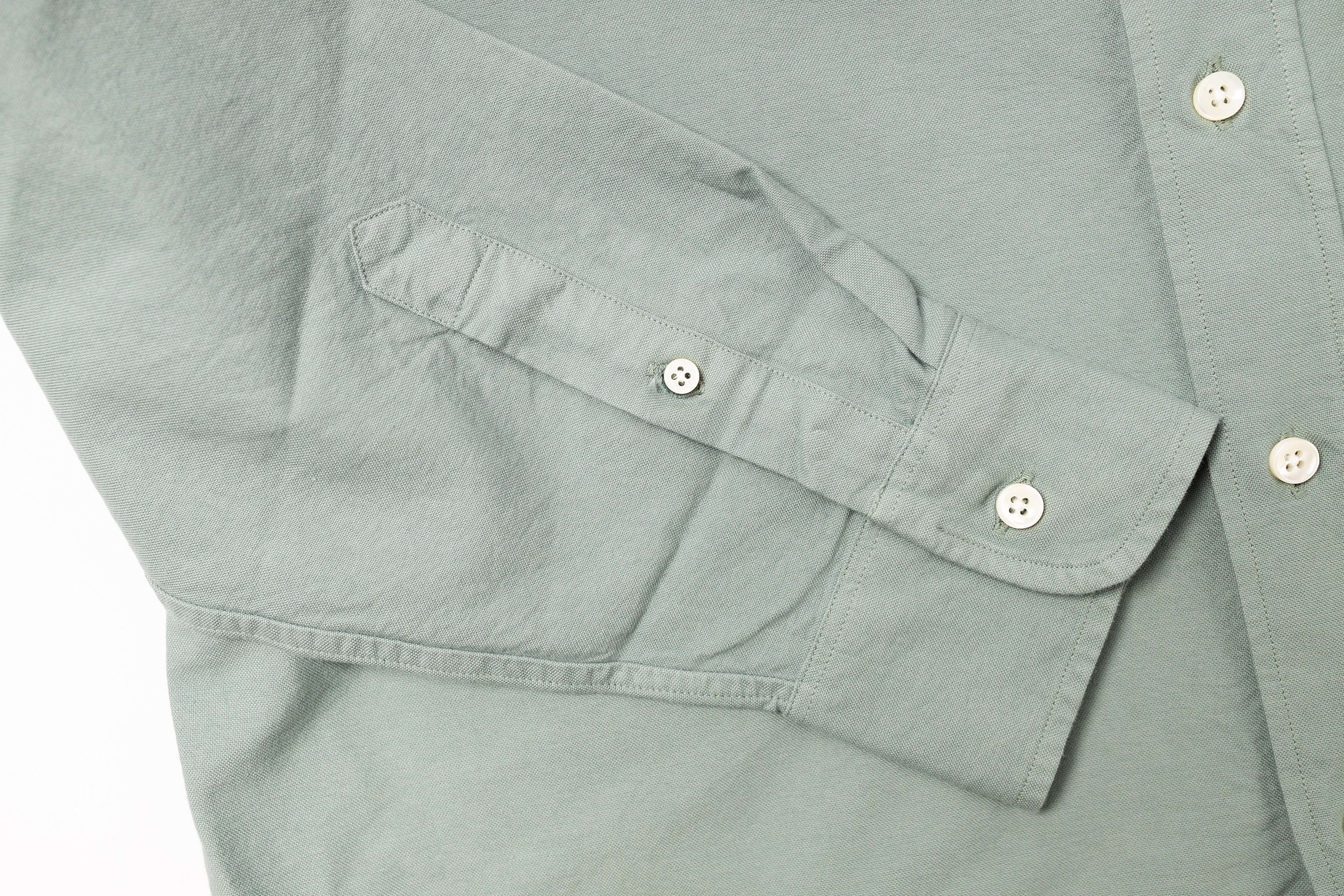 Close-up of a light gray shirt with button details on a white background
