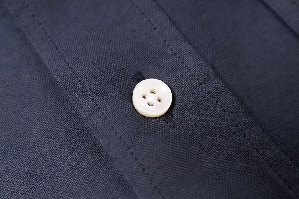 Close-up of a white button on navy blue fabric
