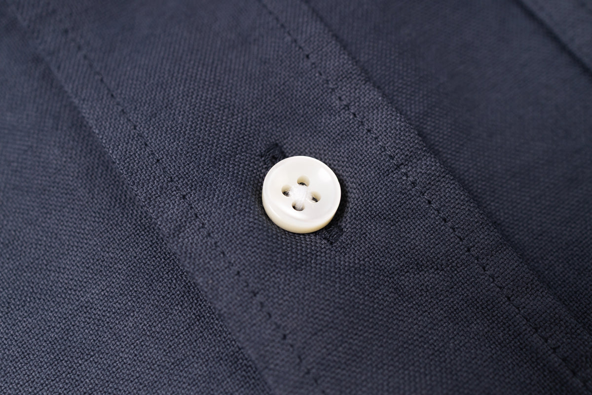 Close-up of a white button on navy blue fabric