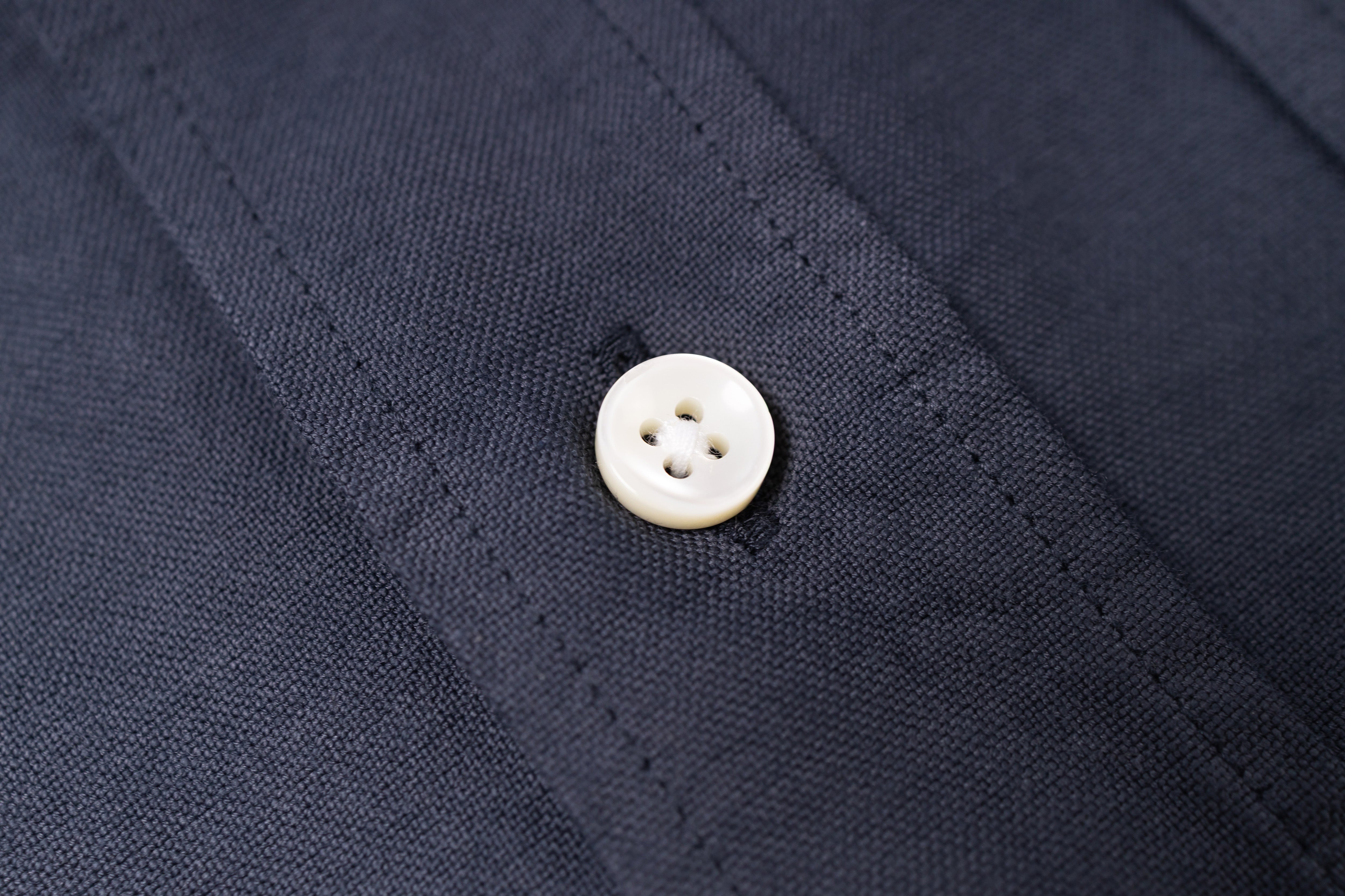 Close-up of a white button on navy blue fabric