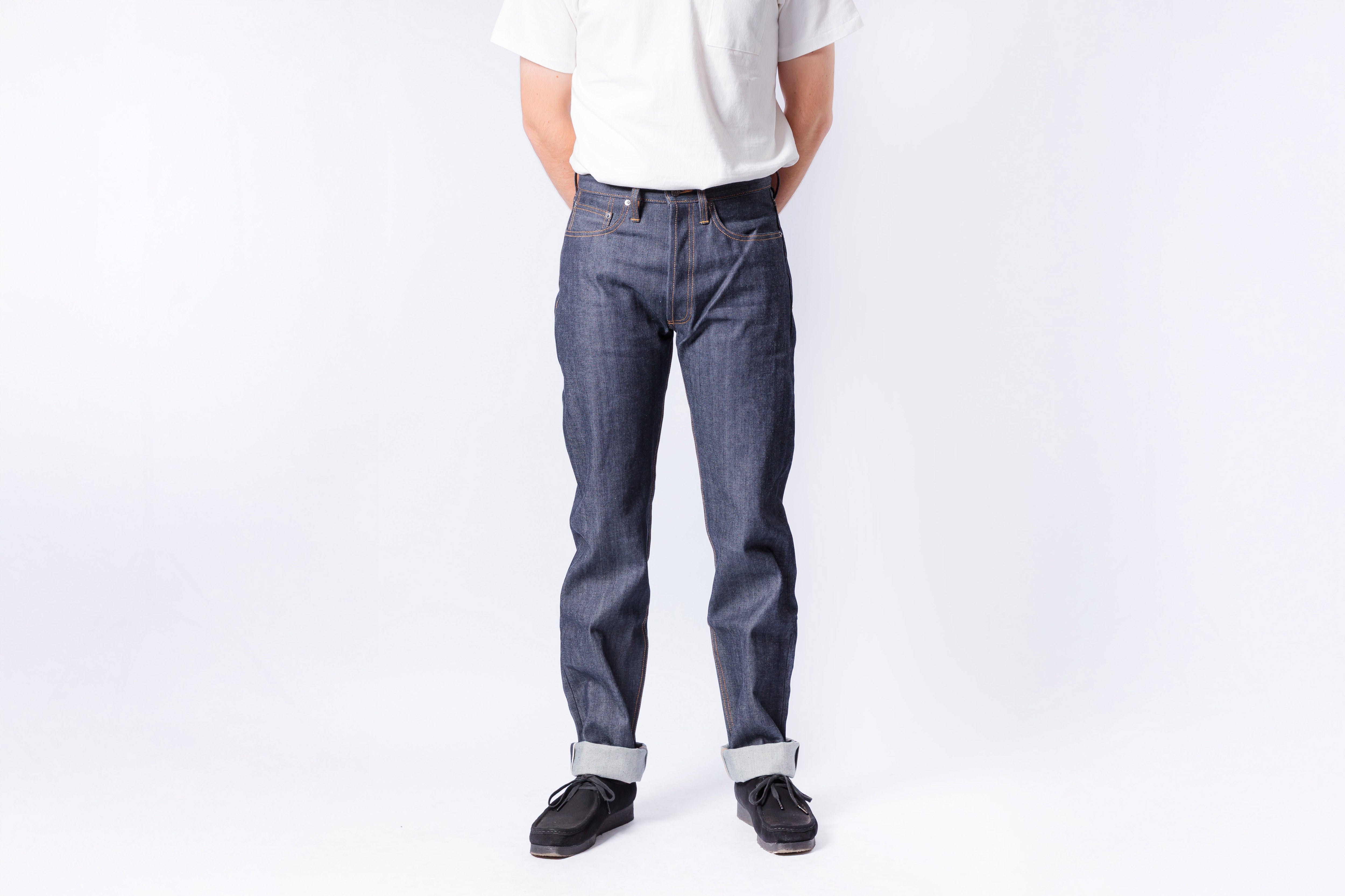 Person wearing blue jeans and a white shirt on a plain background