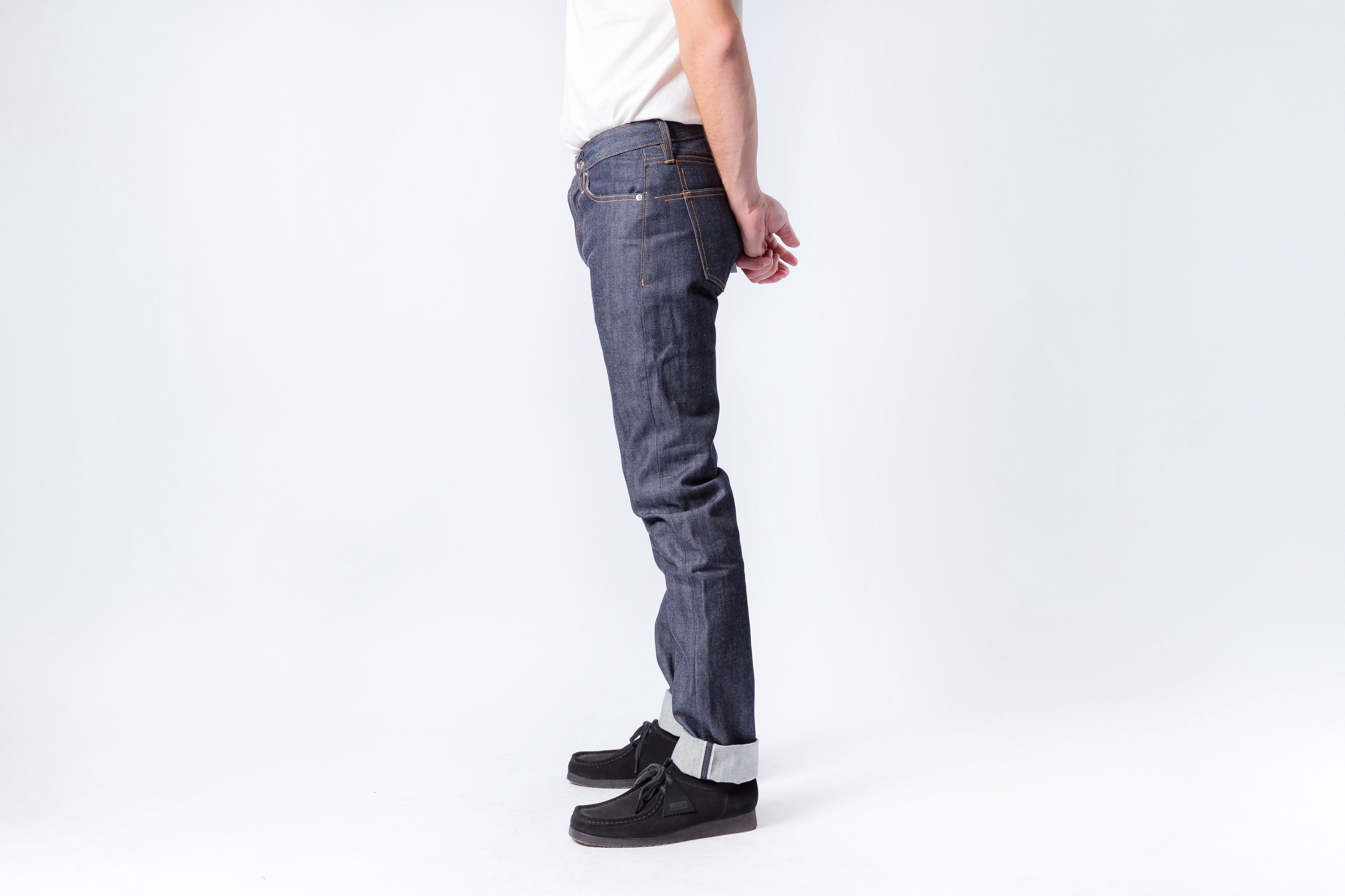 Person wearing blue jeans and black shoes on a white background